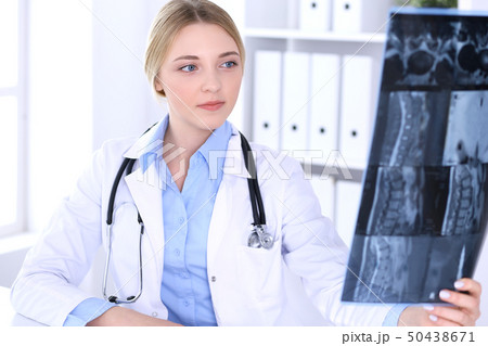 Doctor woman examining x-ray picture near window in hospital. Surgeon or orthopedist at work Doctor woman examining x-ray picture near window in hospital. Surgeon or orthopedist at work 50438671