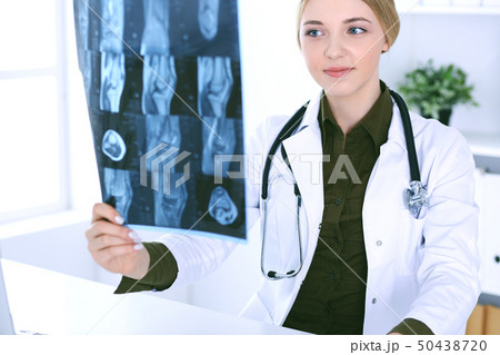 Doctor woman examining x-ray picture near window in hospital. Surgeon or orthopedist at work 50438720