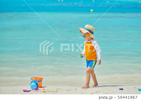 Three year old toddler playing on beach Three year old toddler playing on beach 50441967