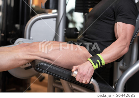 Handsome strong man performed leg press workout in the gym. 50442635