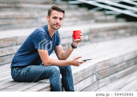 Man is reading text message on mobile phone while walking in the park Man is reading text message on mobile phone while walking in the park 50442693