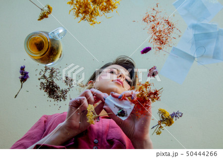 girl from under glass table while she prepares leaves before brew a tea 50444266