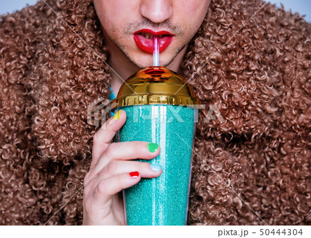 man with lipstick and polish nail holding cocktail 50444304