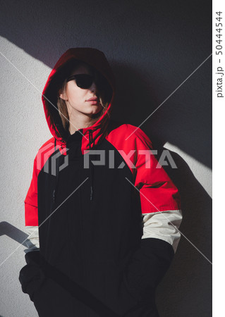 girl in jacket with hood stay on balcony with shadows. girl in jacket with hood stay on balcony with shadows. 50444544