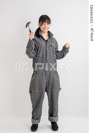 白背景スタジオ撮影作業服をきた女の子がドライバーを持って作業をしている全身工業女子の写真素材