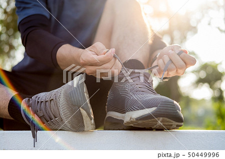 Male athlete tying shoe laces in minimalistic Male athlete tying shoe laces in minimalistic 50449996