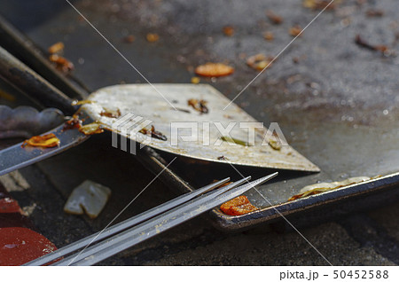 バーベキューを終え、使い終わったヘラと串を鉄板の端にそっと置く 50452588