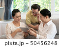 senior asian firend sitting on sofa using digital 50456248