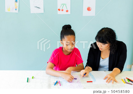 Preteen African American kid alongside with Asian teacher teaching arts 50458580