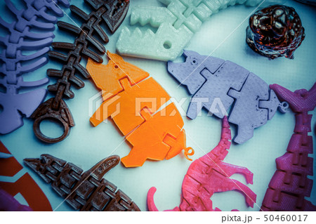 Many bright multi-colored objects printed on 3d printer lie on flat surface 50460017