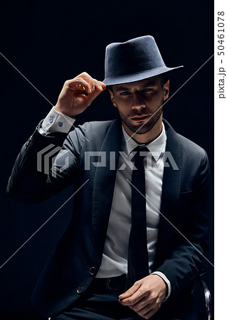 Young handsome man in black suit touch his hat on 50461078