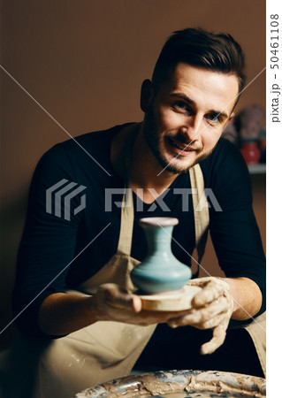 Smiling handsome man showing handmade ceramic pot 50461108