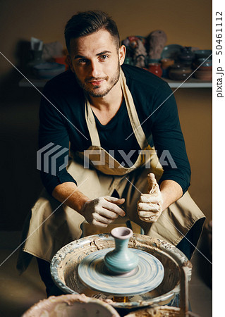 Smiling handsome man showing handmade ceramic pot 50461112