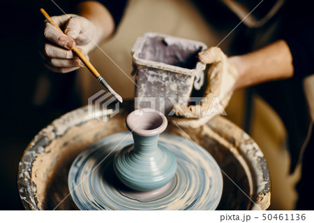 Man painting handmade pottery at ceramic workshop 50461136