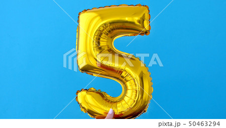 Gold foil number 5 celebration balloon on a blue Gold foil number 5 celebration balloon on a blue 50463294