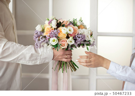 Man stretches out his hands and gives a large bouquet of flowers from roses and lilacs isolated Man stretches out his hands and gives a large bouquet of flowers from roses and lilacs isolated 50467233