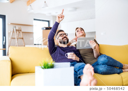 A young couple with tablet sitting on sofa, moving in new home. A young couple with tablet sitting on sofa, moving in new home. 50468542