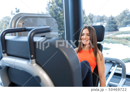 Slim smiling woman using a leg press machine and 50469722