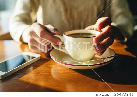 Woman holding in hands cup of coffee on wooden background 50473349