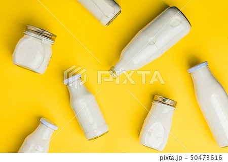 Various bottles of milk on yellow background 50473616