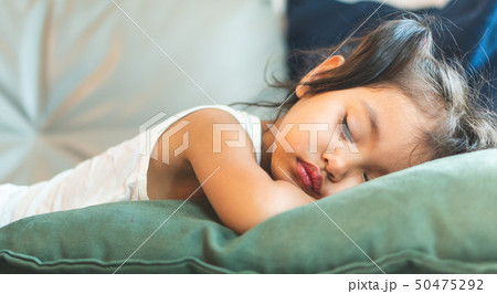 The little girl is sleeping on the bed. 50475292