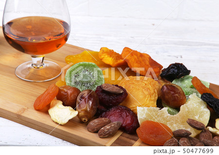 Organic Healthy Assorted Dried Fruit and glasses with cognac or whiskey on wine board. Selective 50477699