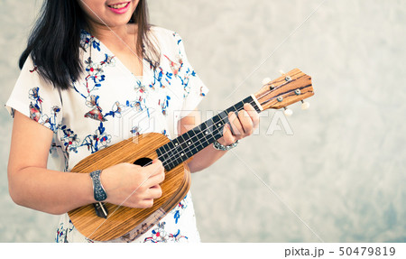 Happy woman musician playing ukulele in studio. Happy woman musician playing ukulele in studio. 50479819