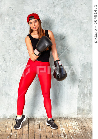 Beautiful young girl boxing gloves near the wall. Beautiful young girl boxing gloves near the wall. 50491451