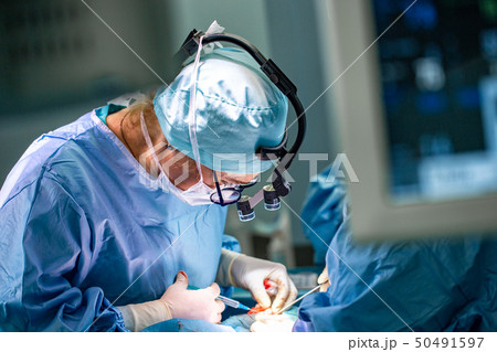 Surgeon and his assistant performing cosmetic surgery in hospital operating room. Surgeon in mask Surgeon and his assistant performing cosmetic surgery in hospital operating room. Surgeon in mask 50491597