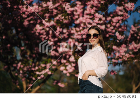 Attractive woman in white shirt in the park. Background of pink tree 50493091