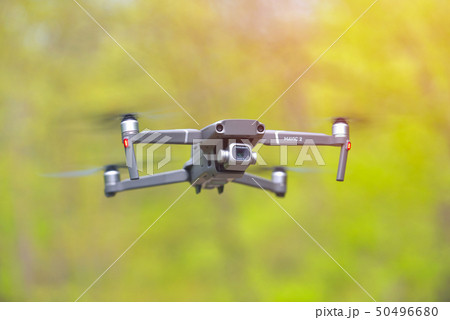 Flying drone with camera hovering inside a forrest 50496680