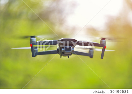 Flying drone with camera hovering inside a forrest 50496681