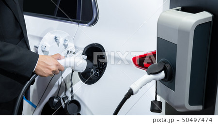 Businessman charging an electric vehicle Businessman charging an electric vehicle 50497474
