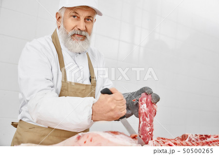 Butcher holding knife and meat, looking at camera. Butcher holding knife and meat, looking at camera. 50500265