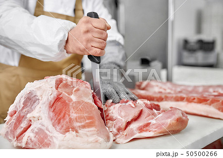 Close up of raw meat and butcher cutting meat with knife. Close up of raw meat and butcher cutting meat with knife. 50500266
