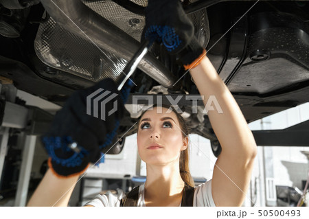 Young woman fixing undercarriage with wrench. Young woman fixing undercarriage with wrench. 50500493