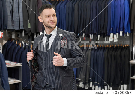 Man doing shopping in boutique, trying on grey stylish suit. 50500868
