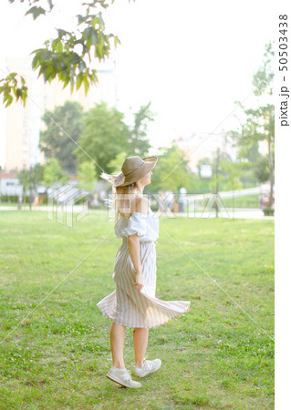 Back view of young girl wearing hat and dress, standing in park. Back view of young girl wearing hat and dress, standing in park. 50503438