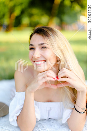 Young smiling caucasian woman lying in park on plaid. 50503530