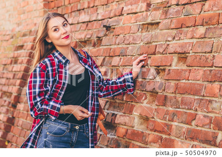 Portrait of young woman standing against brick Portrait of young woman standing against brick 50504970