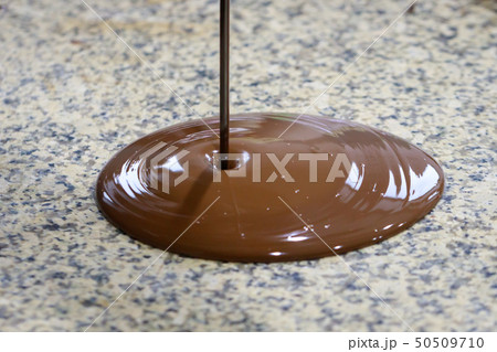Liquid chocolate is poured on a granite table Liquid chocolate is poured on a granite table 50509710