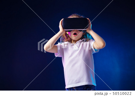 Girl 7 y.o. experiencing VR headset game on colorful background. Surprised emotions on her face 50510022