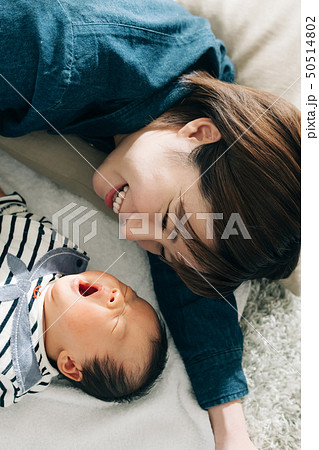 あくびをする赤ちゃんと添い寝する母親 育児 子育ての写真素材