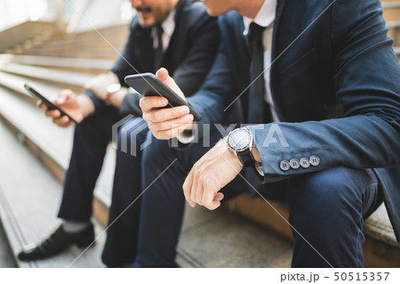 Partners use smartphone discussing at stairway. 50515357