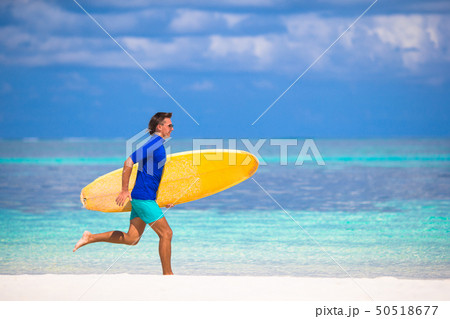 Happy young surf man runing at the beach with a surfboard 50518677