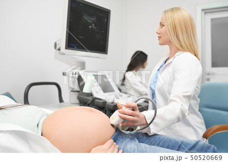Serious doctor in process of doing ultrasound diagnostic Serious doctor in process of doing ultrasound diagnostic 50520669