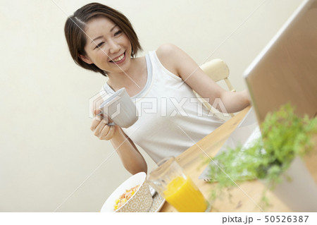 朝食を食べながらパソコンを見ている女性 朝食を食べながらパソコンを見ている女性 50526387