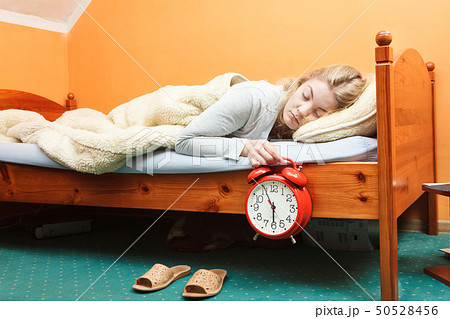 Unhappy woman waking up with alarm clock. Unhappy woman waking up with alarm clock. 50528456