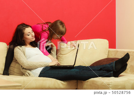 Pregnant woman and daughter sitting with laptop Pregnant woman and daughter sitting with laptop 50528756