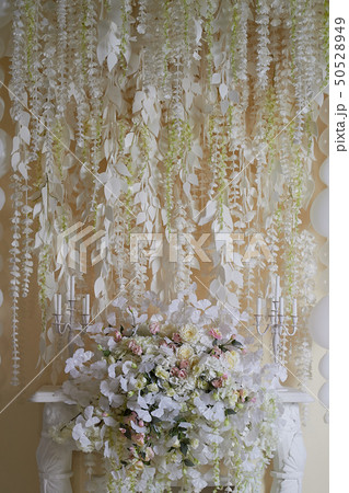 Flower garland on the wall as an element of festive, wedding decor. Light tone.Decorative fireplace. 50528949